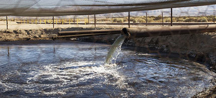 A pipe pours fracking waste into an unlined holding pond in Kern County, California. (photo: Faces of Fracking/Flickr)